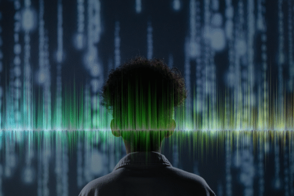 Person standing in front of lines of code, with sound wave spanning width of image