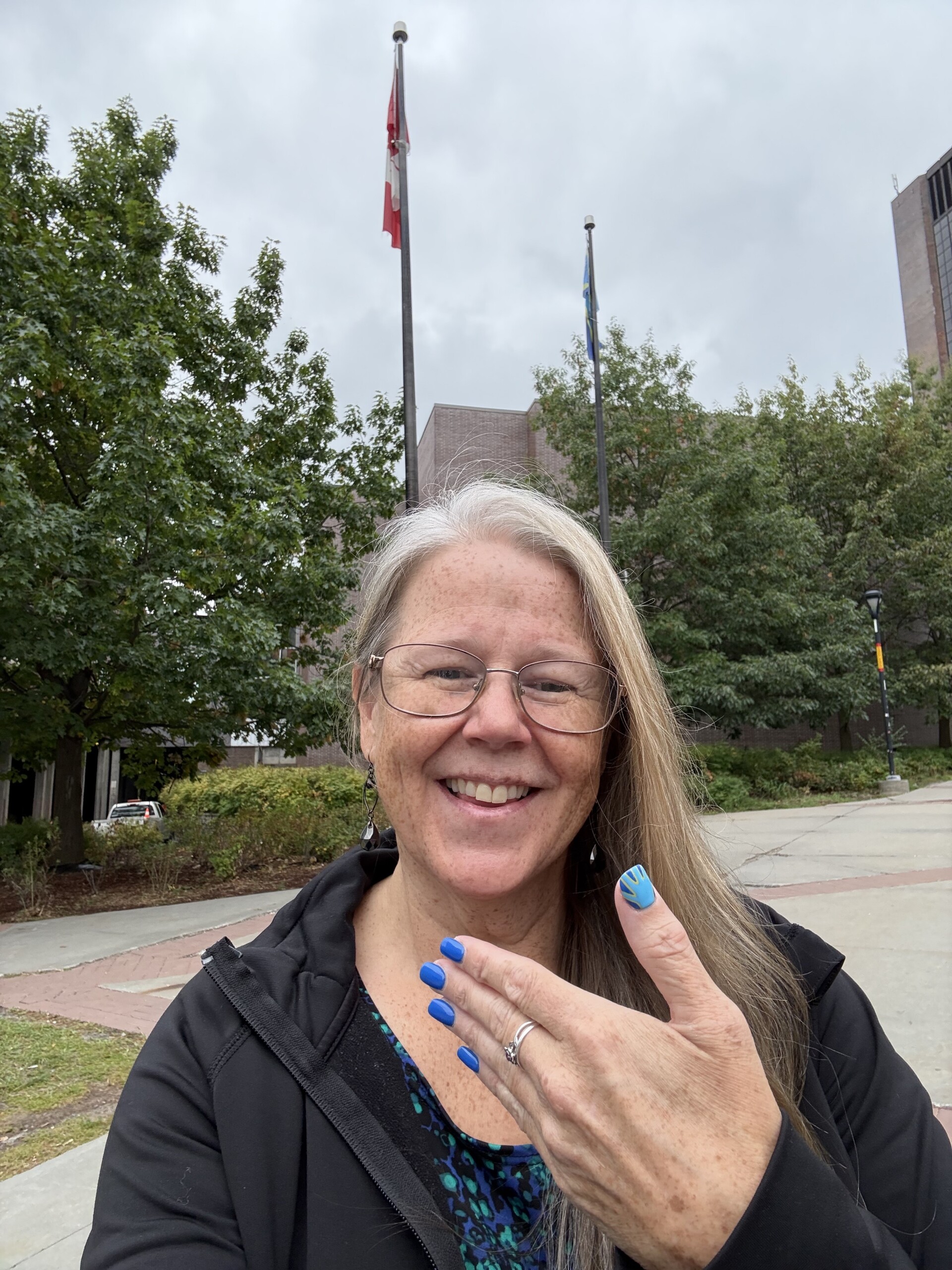 Image of Denise DeShaw in front of the WFD flag at Carleton University