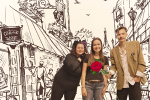 Image of three people standing in front of a street scene that has been sketched