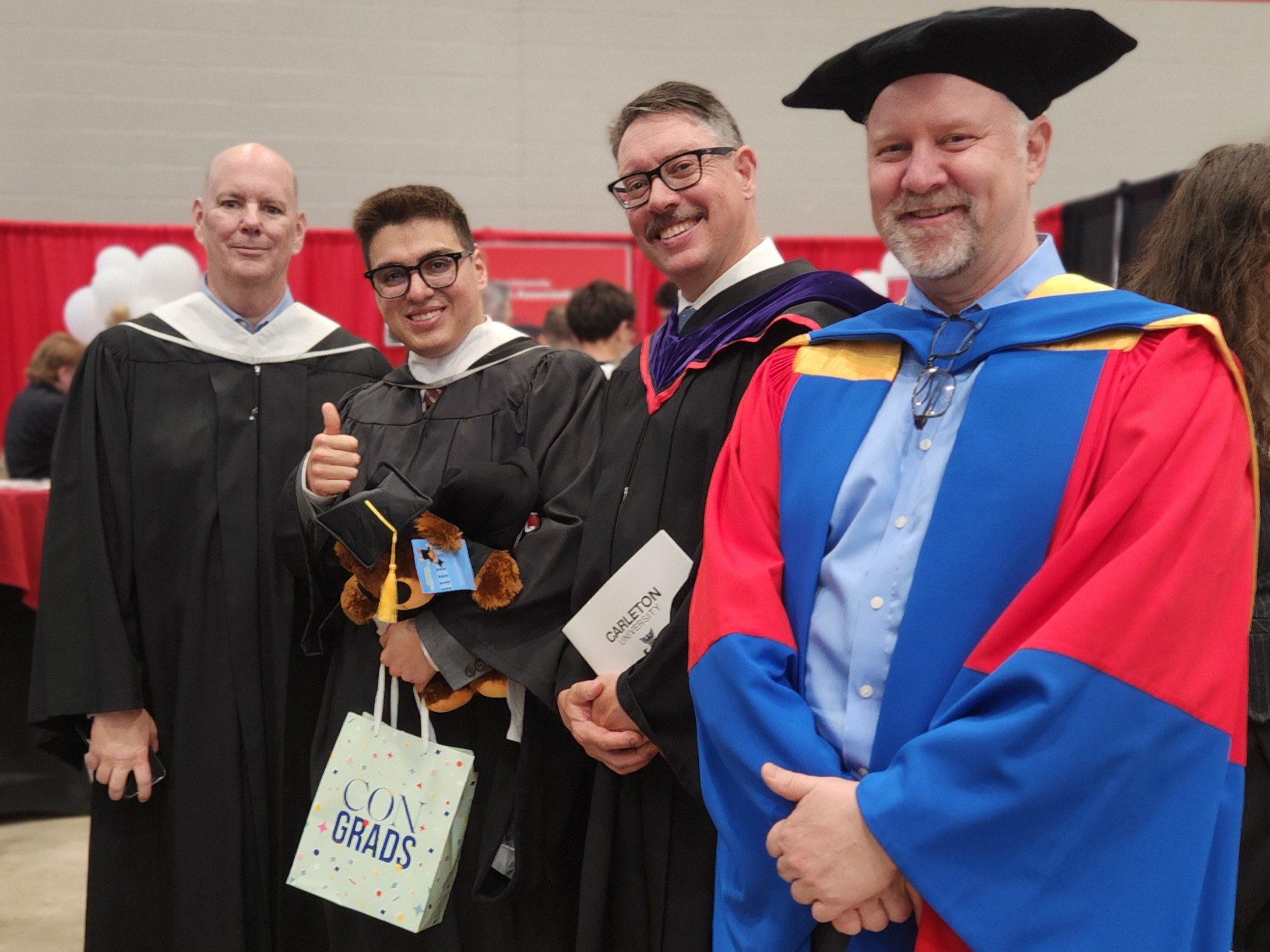 Image of a graduate, Leon, with professors at convocation