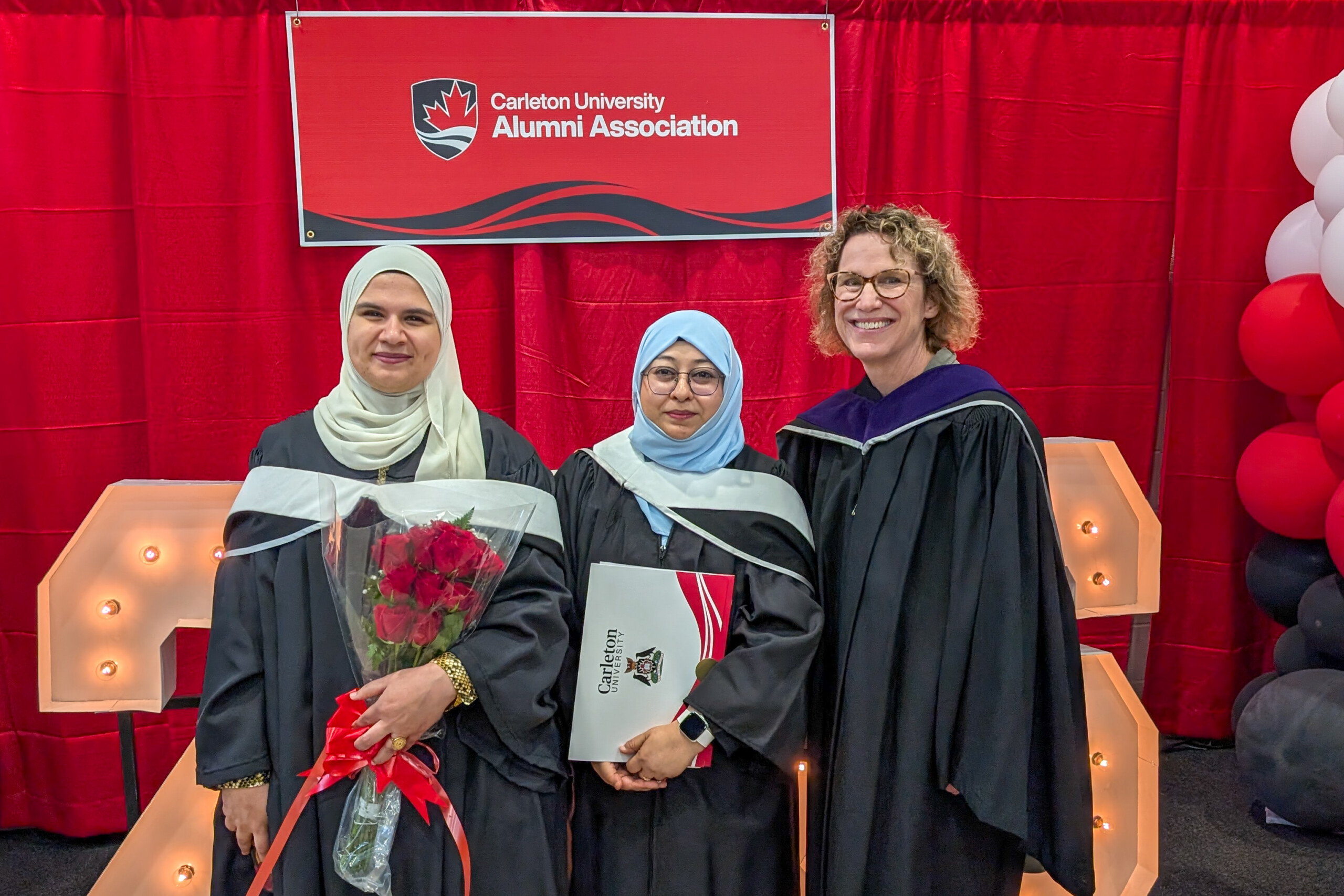 Image of two graduates, Asmaa and Mariam, with professor Peggy Hartwick