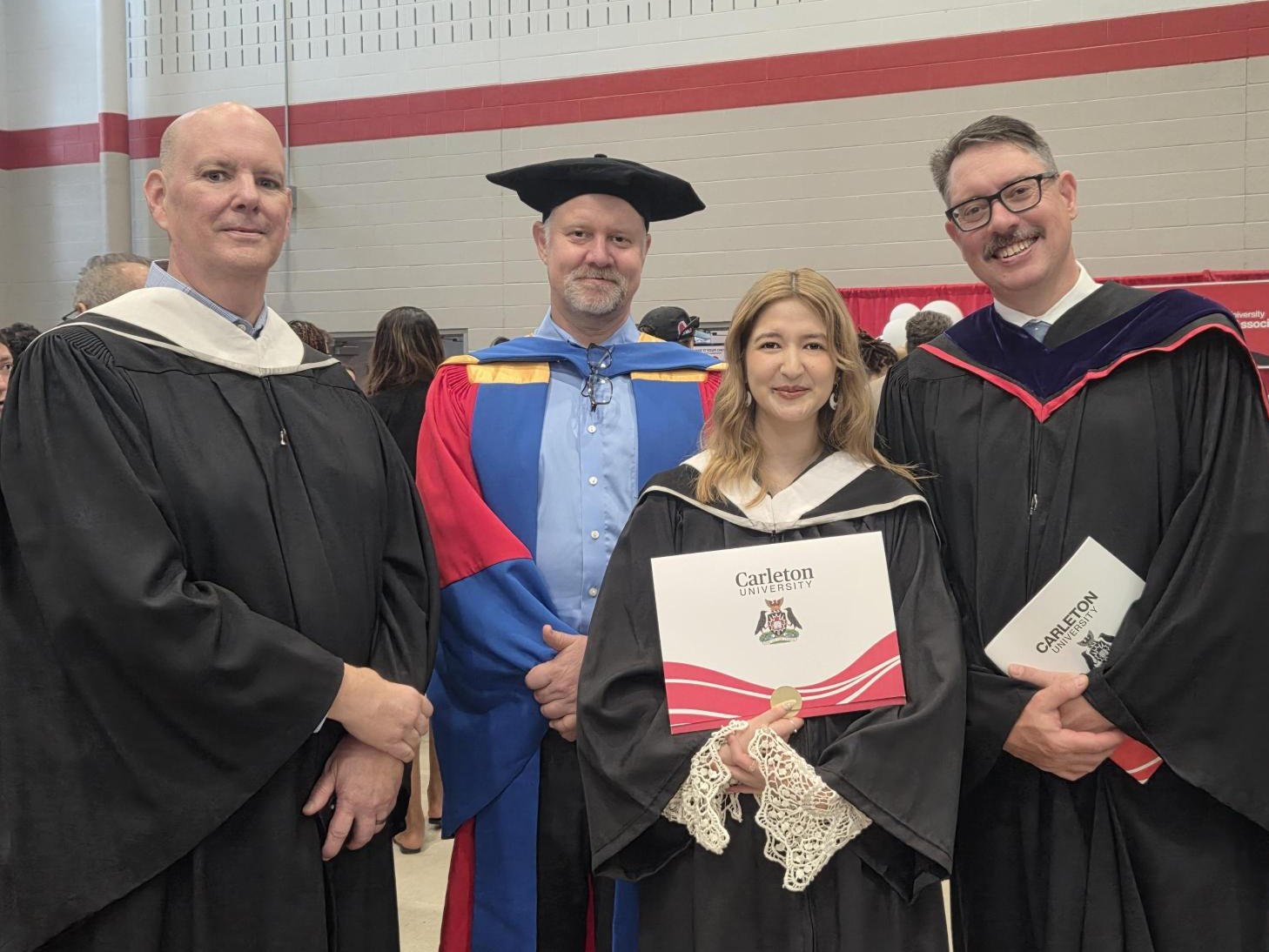 Image of a graduate, Natsumi, with professors at convocation