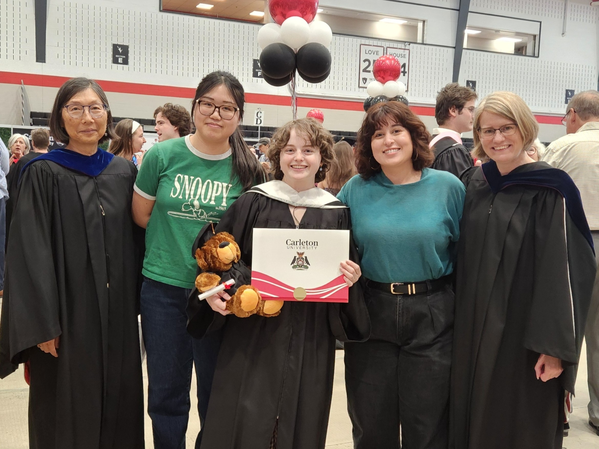 Imagine of a graduate, Thea, with pals and professors at convocation