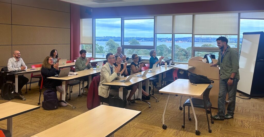Group shot from Youssef's presentation showing the audience and view of Halifax harbour out the window.