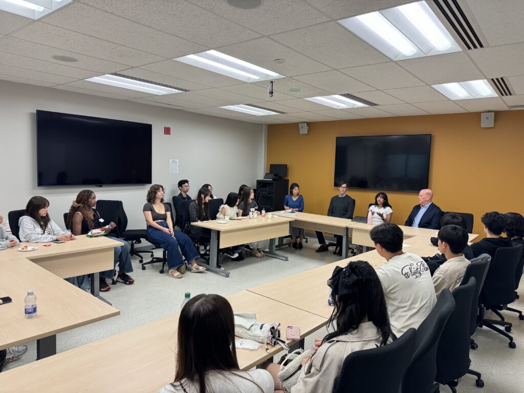 Students and faculty sit around table engaged in discussion.