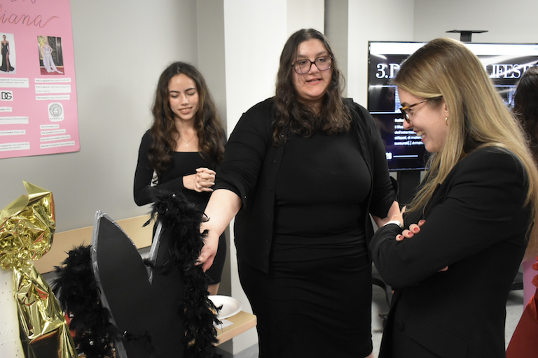 Gabriela and Francesca show off their foam models of popular dress models. Rebecca looks on.