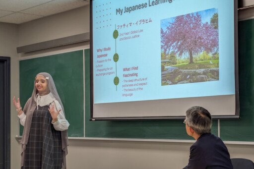 Fatima speaks about her experience learning Japanese. A cherry tree is blossoming on her PPT slide.