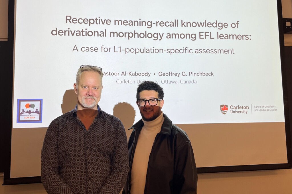 Geoff and Mastoor in front of the intro slide of their presentation