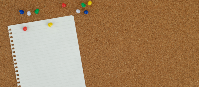 Corkboard with lined paper and push pins