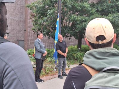 View of Michael Rodgers and David Morton with the flag in the background
