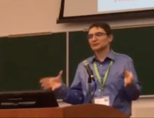 screenshot of Guillaume standing at the conference podium
