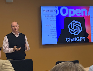 Don standing in front of the ChatGPT logo on his presentation.