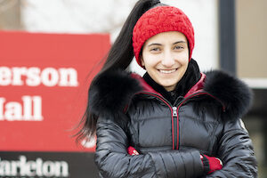 Talia stands in front of Paterson Hall sign with arms crossed
