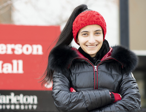 Talia stands in front of Paterson Hall sign with arms crossed