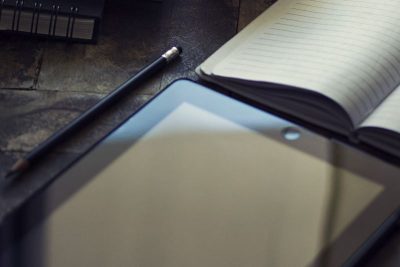 padlet, blank lined notepad, and pencil on table