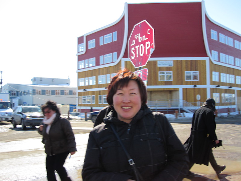 Maria in front of a stop sign written in Inuktitut
