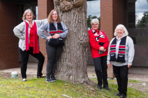 Four individuals standing by a tree