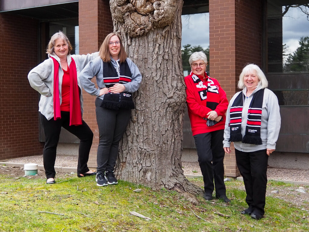 Four individuals standing by a tree