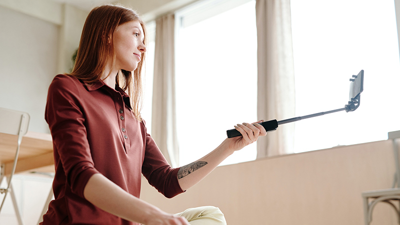 A woman in red long sleeve shirt holding a selfie stick