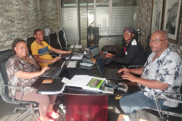 Image of Sharon Gabie, Wilard Veldskoen, Boetles Gewers, and James Mapanka organizing fieldwork materials.