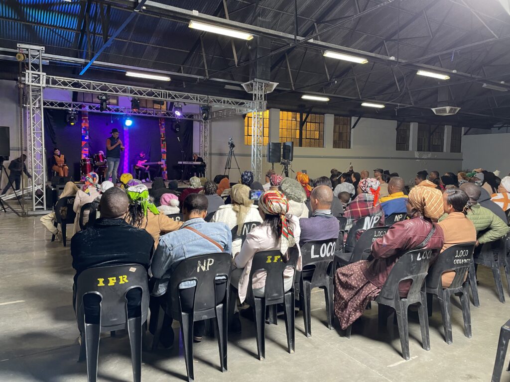 Image of a gospel show with purple lighting and a seated audience