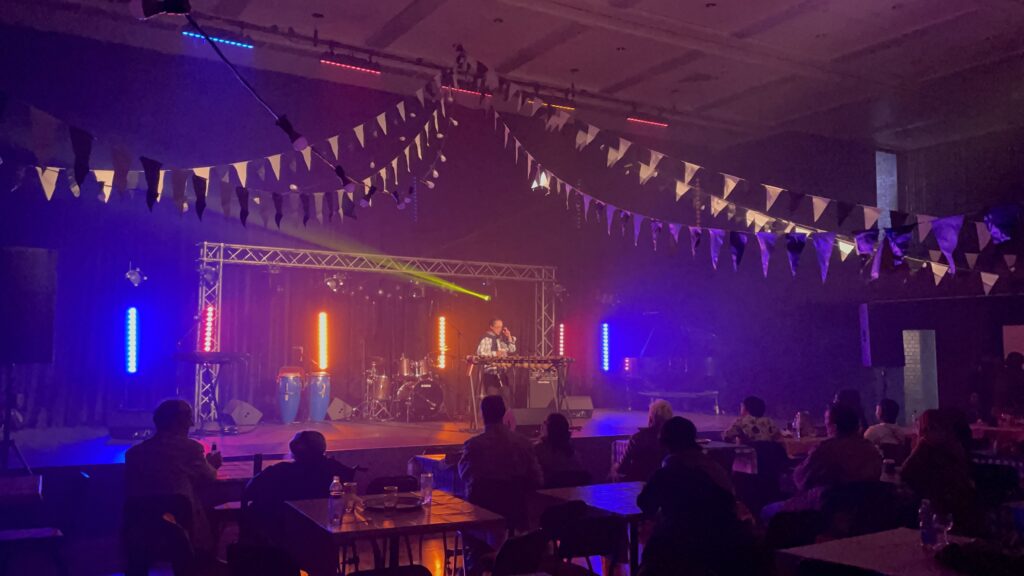 Image of Dr. Lee Watkins speaking on a stage with orange, blue, and purple lighting.
