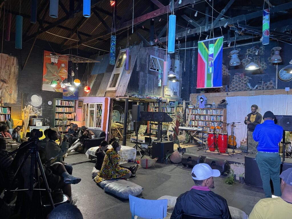 Xolie Madinda preparing to speak at an event venue. There are bookshelves in the background.