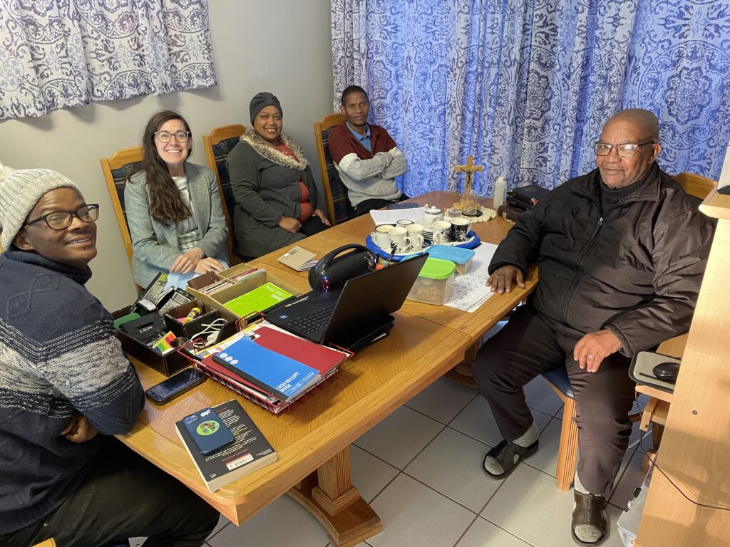Image of Boetles Gewers, Lyndsey Copeland, Sharon Gabie, Wilard Veldskoen, and James Mapanka sitting around a wooden table.