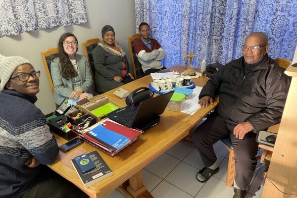 Image of Boetles Gewers, Lyndsey Copeland, Sharon Gabie, Wilard Veldskoen, and James Mapanka sitting around a wooden table.