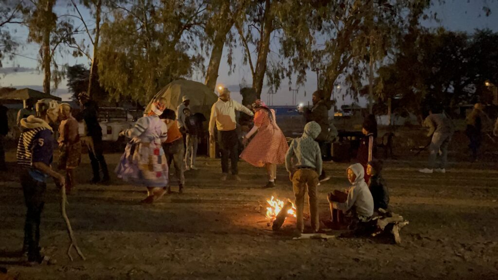 An image of people dancing around a fire in the "Cultural Village" during the 2024 Nama Cultural Festival.