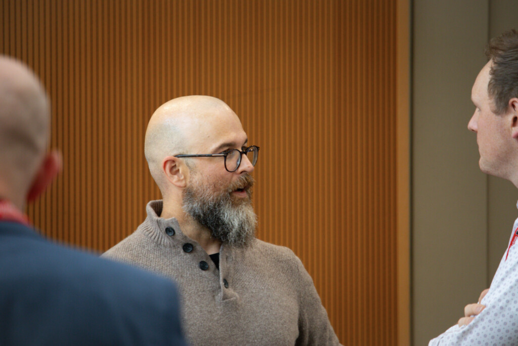 Two attendees converse at the SPPA Alumni Reception in front of a wood-paneled wall.