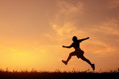 decorative photo showing a silhouette of someone running in a field.