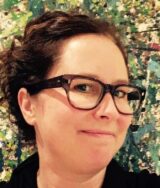 A photo of Tammy Maker, wearing black glasses with her hair in a ponytail