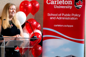 Thumbnail image of Jennifer Stewart, SPPA Director, standing at podium with balloons behind
