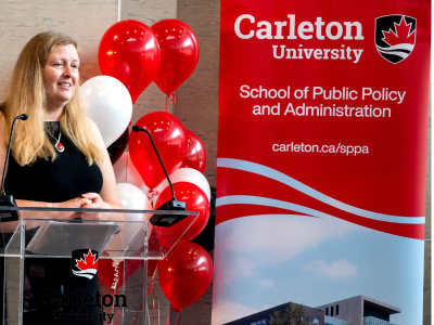 Thumbnail image of Jennifer Stewart, SPPA Director, standing at podium with balloons behind
