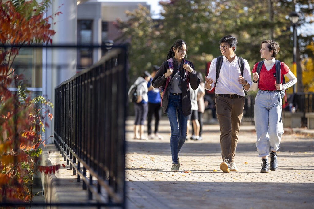 Three students walk along a path next to Tory Building