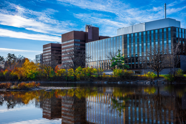 Campus buildings reflecting in the Rideau River on a still day
