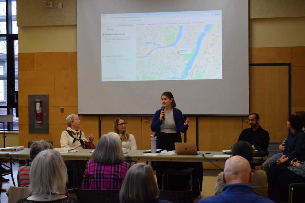 Woman speaking in front of an audience with digital map displayed in background