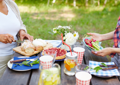 Reusable dishware with food and drinks on a picnic table.