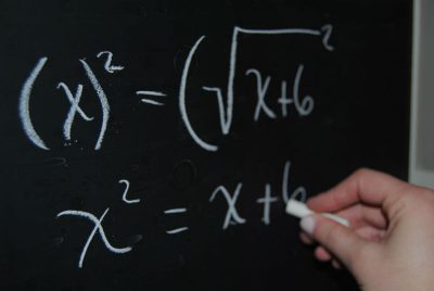 Mathematics equations being written on a blackboard