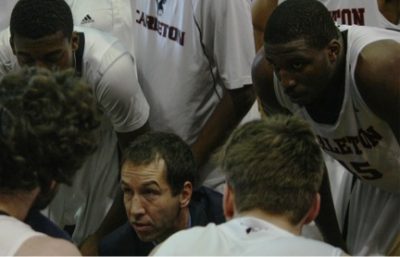 Rob Smart sits in a huddle with the Ravens men's basketball team