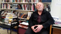 Bill Skidmore sits in front of a bookcase