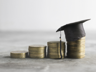Four piles of gold coins with a graduation cap on top of one