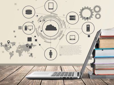 Laptop lening on a stack of books. A high-tech illustration appears above.