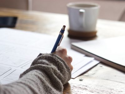Someone writes at a desk using a mechanical pencil.