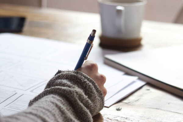 Someone writes at a desk using a mechanical pencil.