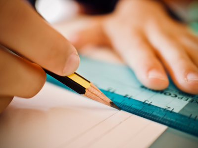 A person drawing a horizontal line with a ruler