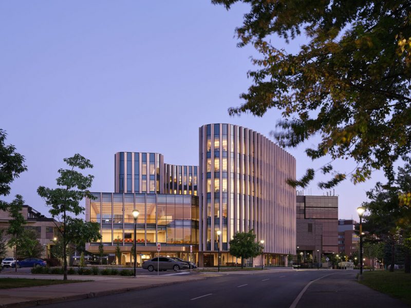 Photograph of the exterior building of the Sprott School of Business lit up in the evening