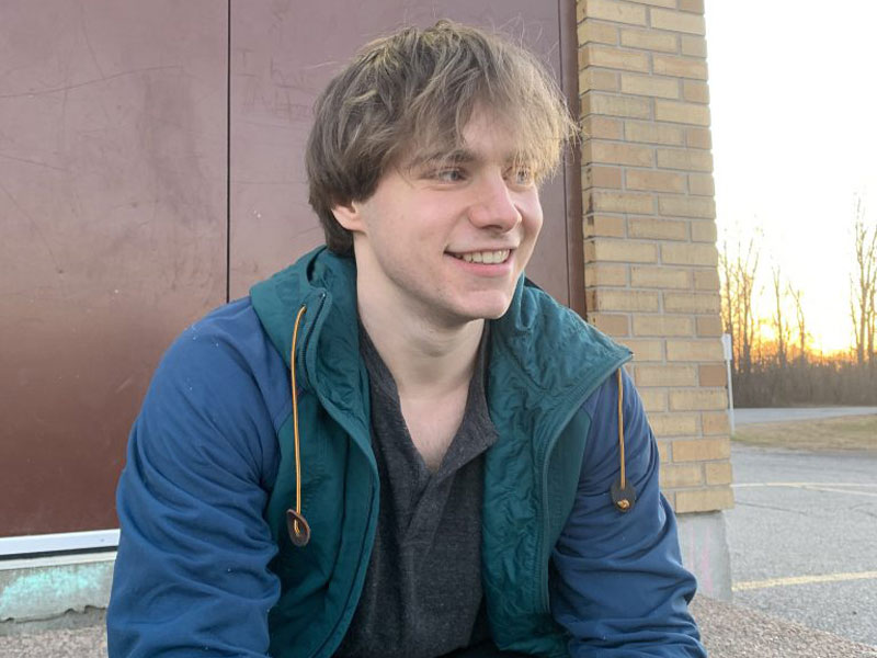 Isaac sits on a set of steps outside a building.