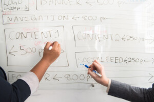 Web Designers draw a site map on a whiteboard.